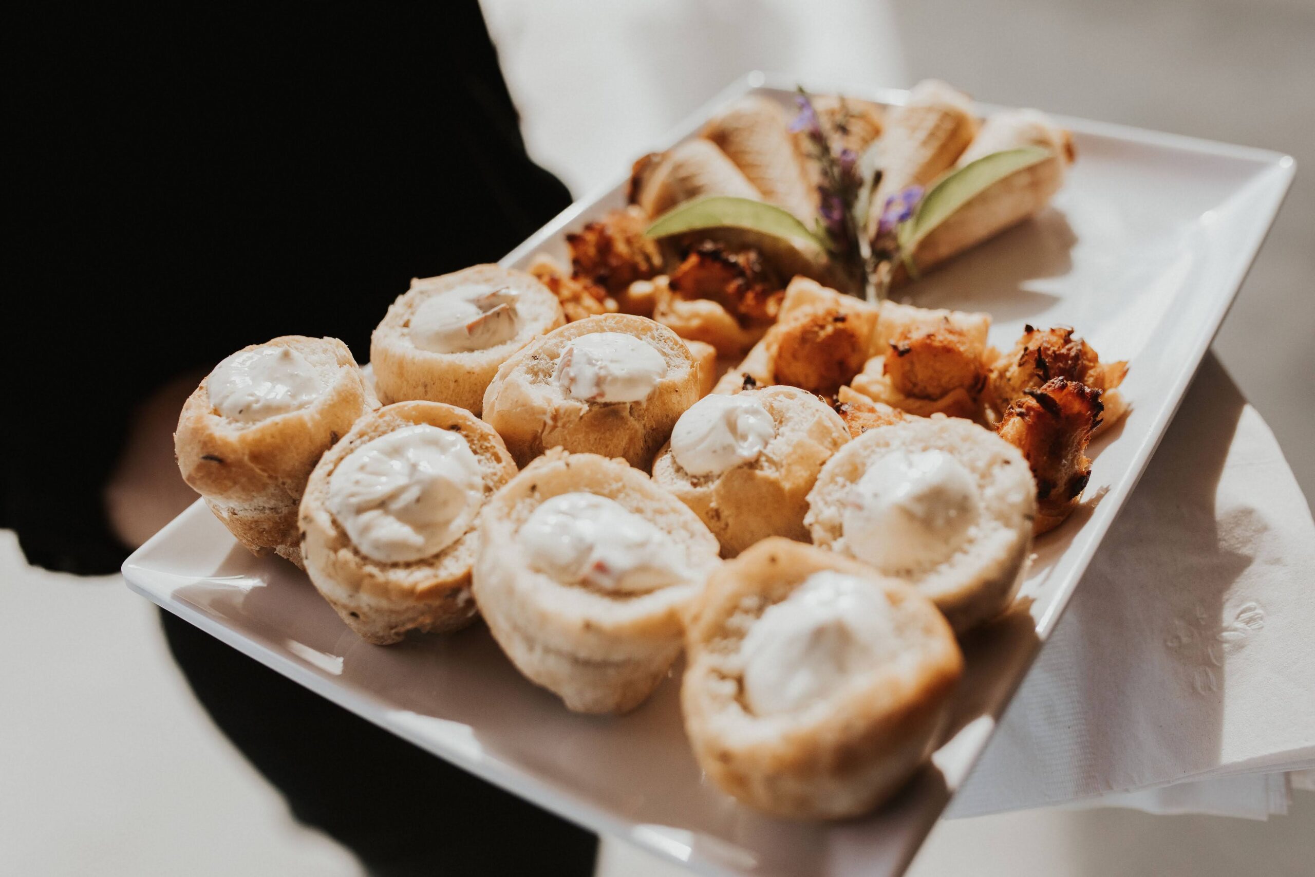 Assorted Handpassed Appetizers Hand-passed bridal platter featuring rye dip bread bowls, buffalo chicken dip cups, and miniature chicken and waffle cones, showcasing a variety of delicious appetizers for weddings