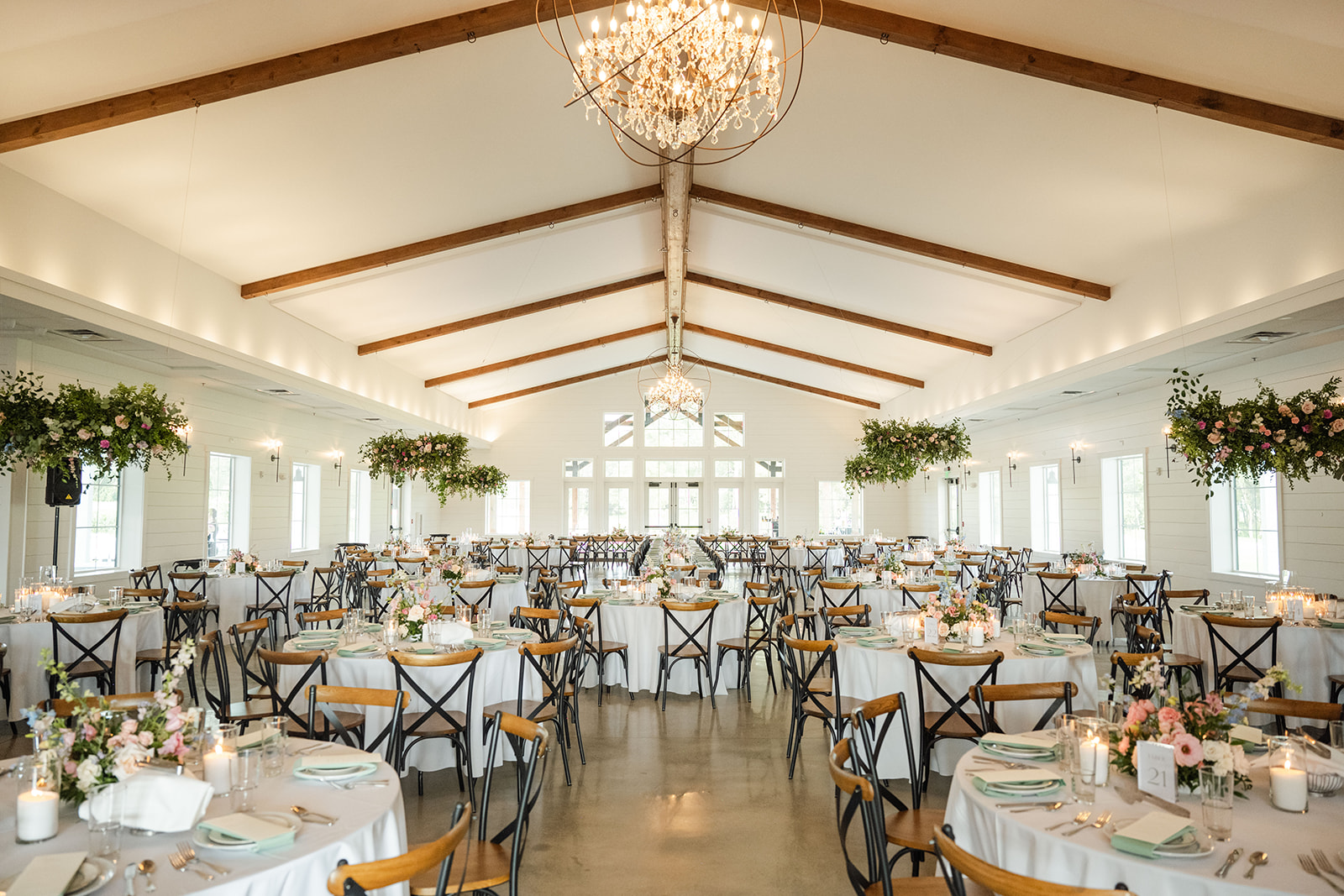 The Annex- Interior Elegant interior of The Annex beautifully decorated for a wedding event, featuring lush florals, soft candlelight, table numbers, luxurious linens, and meticulously arranged place settings, creating a romantic and sophisticated atmosphere.