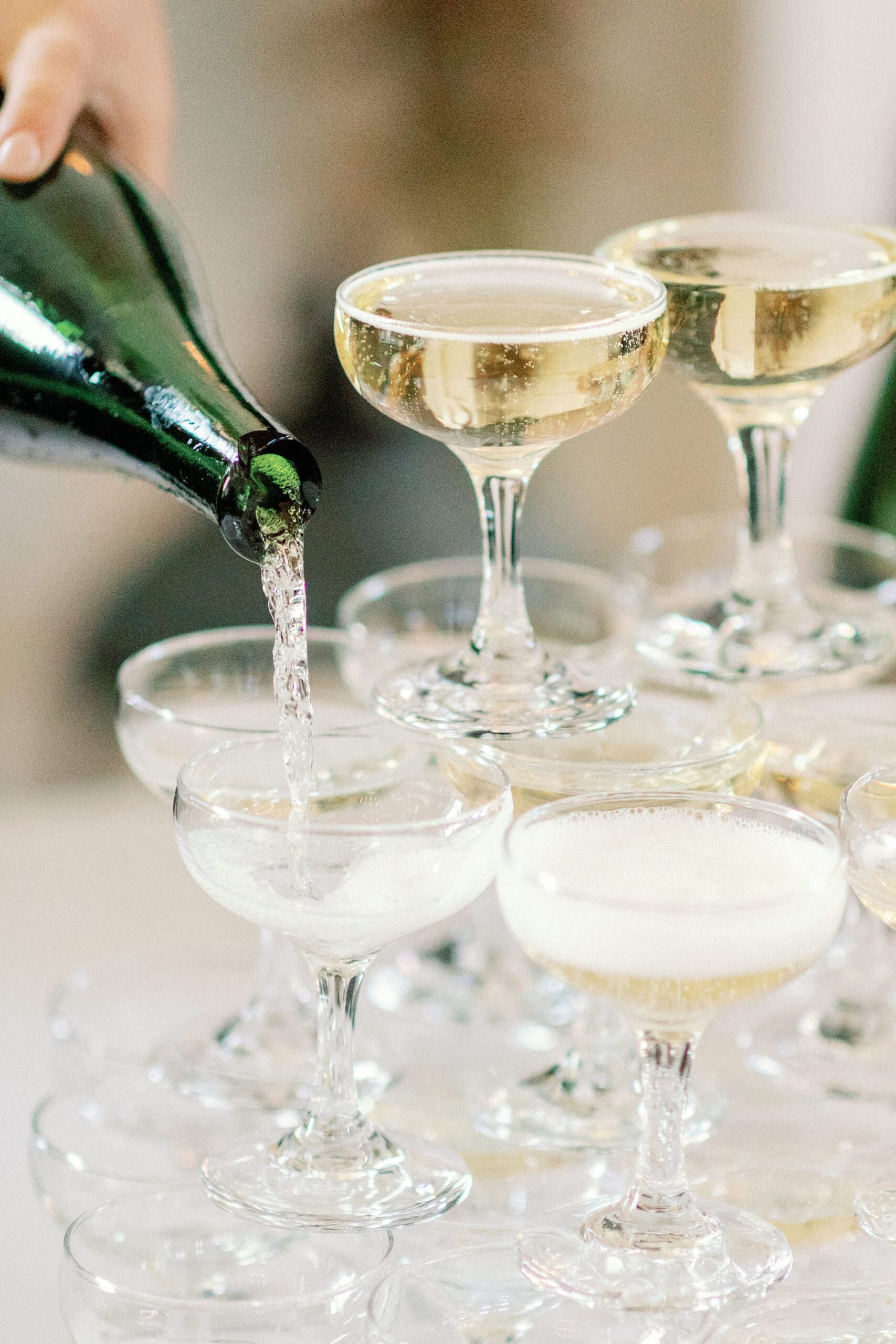 Champagne Pour for a Champagne Toast A close-up photo of a champagne pour, into the top glass of a cascading champagne tower, with bubbles forming as the liquid overflows into the glasses below.