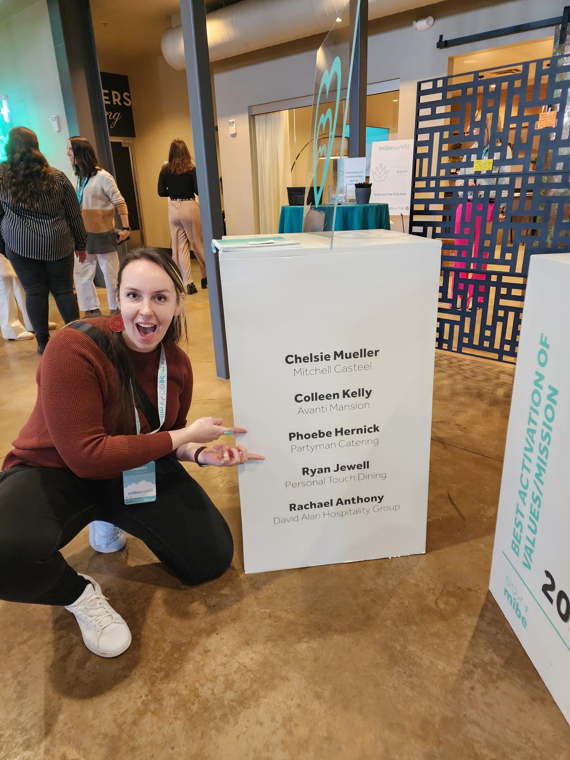 2025 MIBE Summit A sous chef kneeling and pointing to their name on an award nomination box at the 2025 Mibe Summit for the 2024 awards.