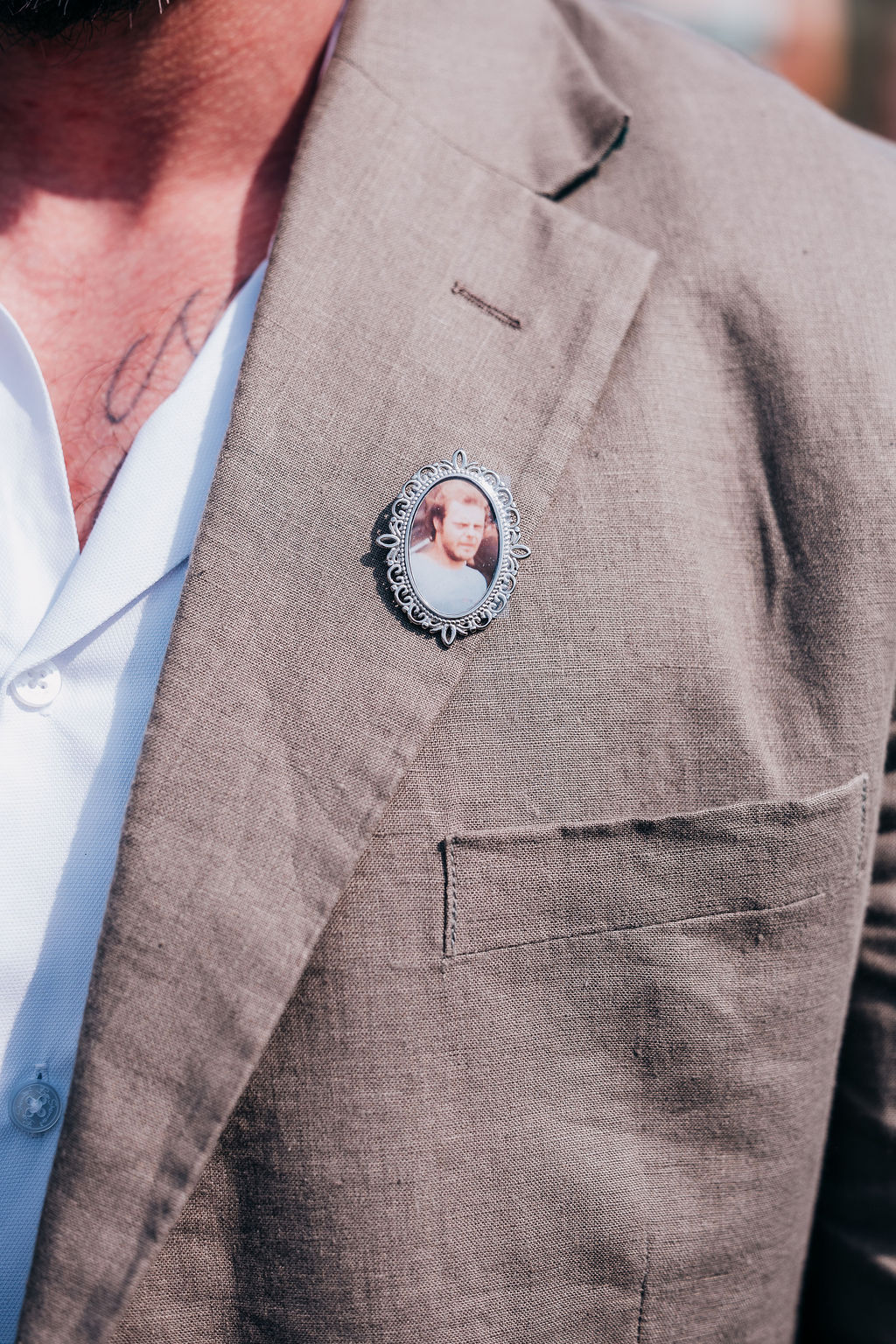 Sentimental Brooch Keepsake Close-up of a groom’s suit jacket with a vintage photo brooch pinned to the lapel.