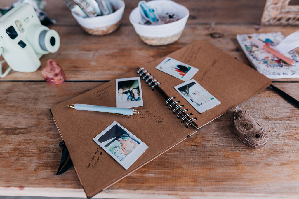 Wedding Guestbook with Polaroids Open guest book with instant photos and handwritten notes, styled with pens and keepsakes on a wooden table.