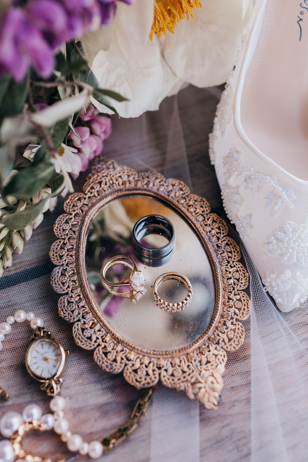 Wedding Rings on Heirloom Tray Trio of wedding rings placed on a vintage gold tray, surrounded by flowers and jewelry.