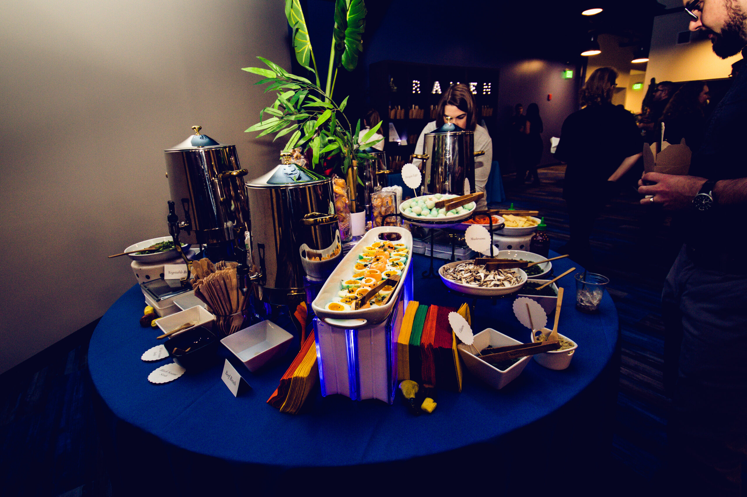Vibrant Event Catering Display A round catering display table with a colorful spread of food, drinks, and garnishes, set up for a corporate event.