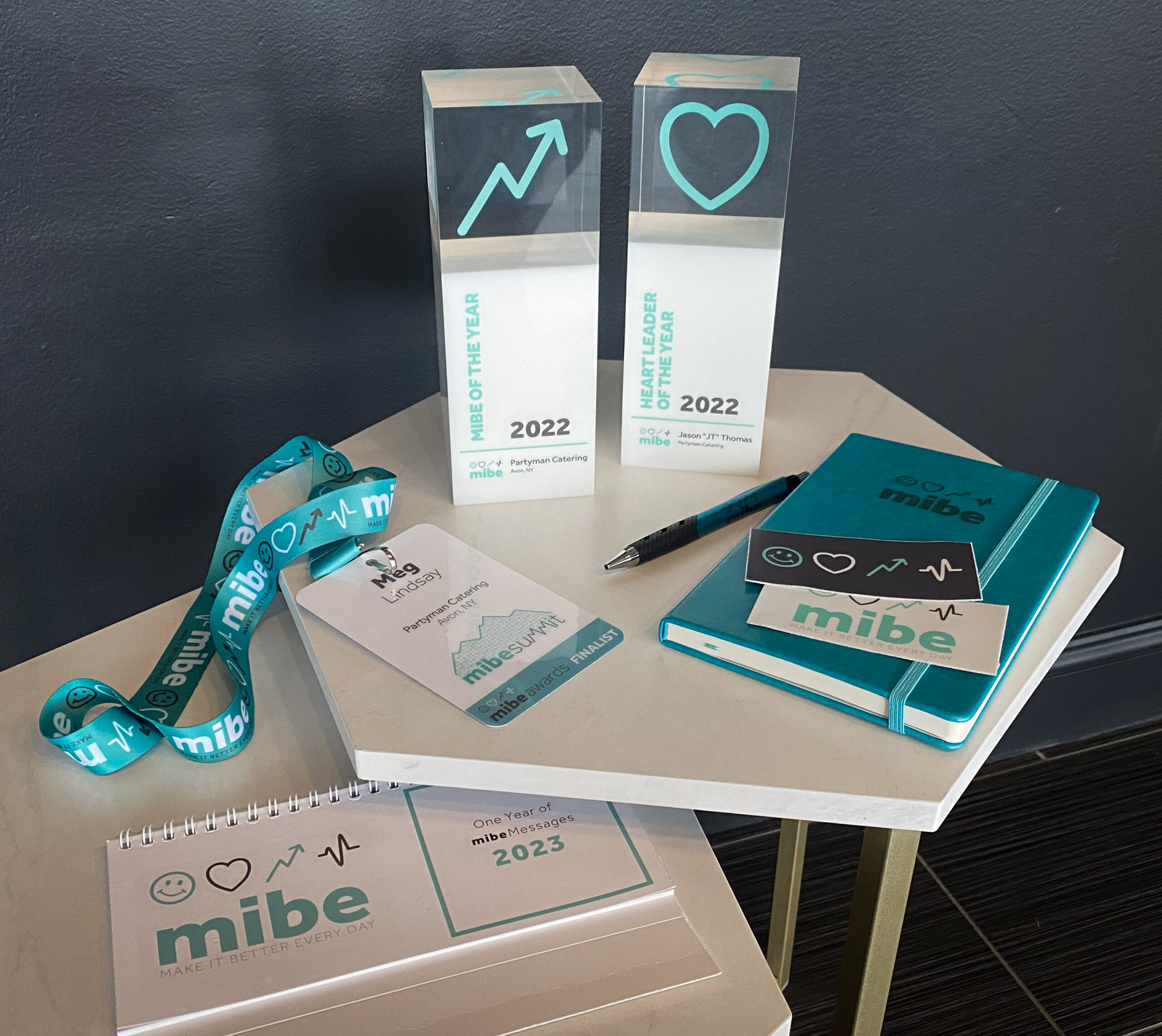 Partyman Catering Celebrates MIBE 2022 Award Wins Display of Partyman Catering’s MIBE 2022 trophies for MIBE of the Year and Heart Leader of the Year, alongside branded notebooks, lanyards, and awards materials.