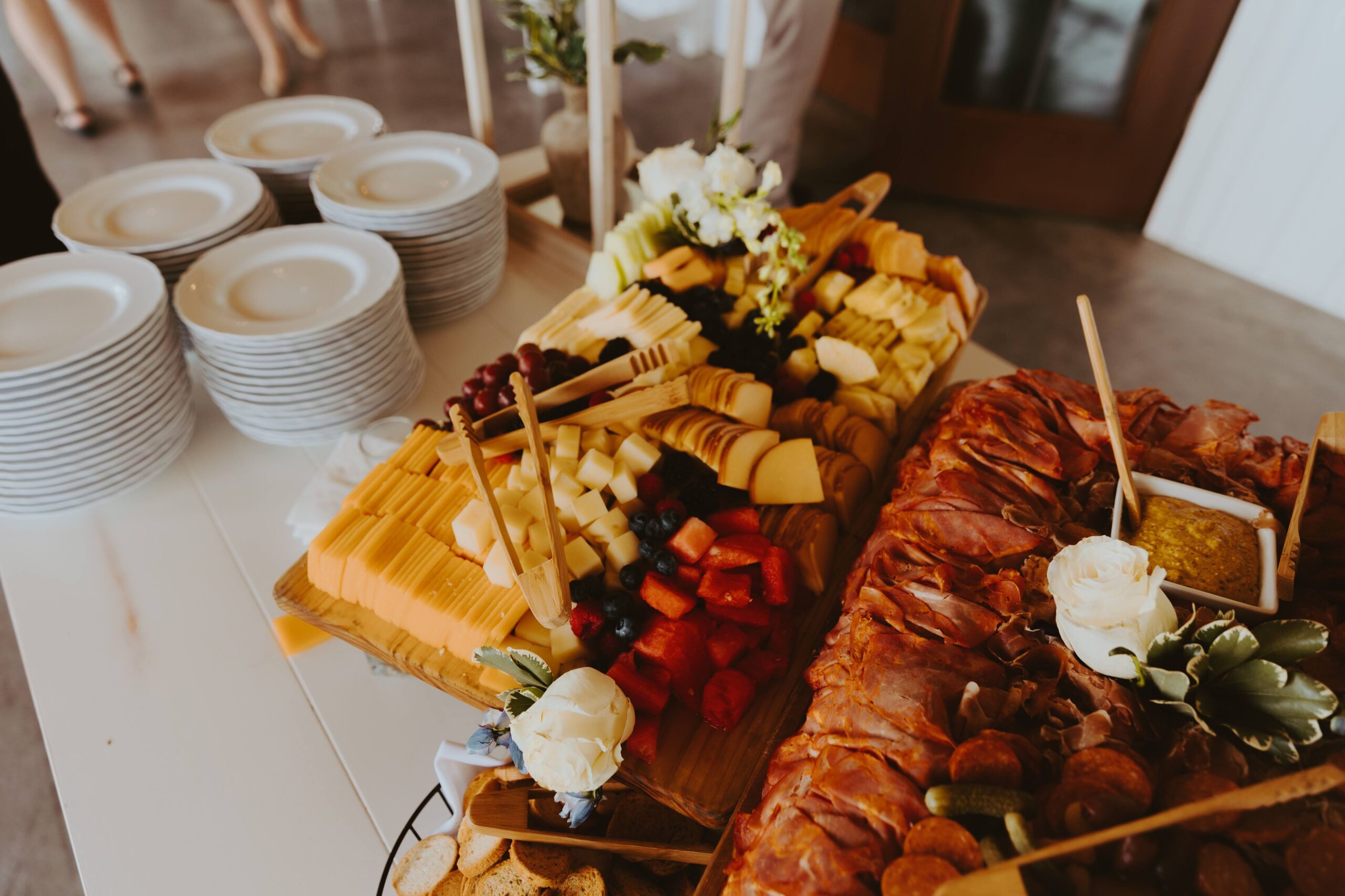 Rustic Charcuterie Board with Cheese, Fruit, and Meats at Wedding Reception Large grazing board display with assorted cheeses, fresh fruit, cured meats, and mustard dip, styled for a cocktail hour.