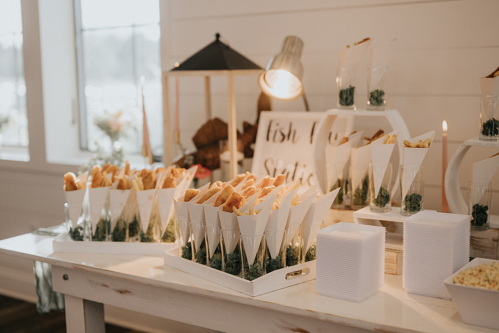 Elegant wedding catering display featuring a fish fry station with handheld cones of fried fish and fries, styled as an interactive seafood experience.