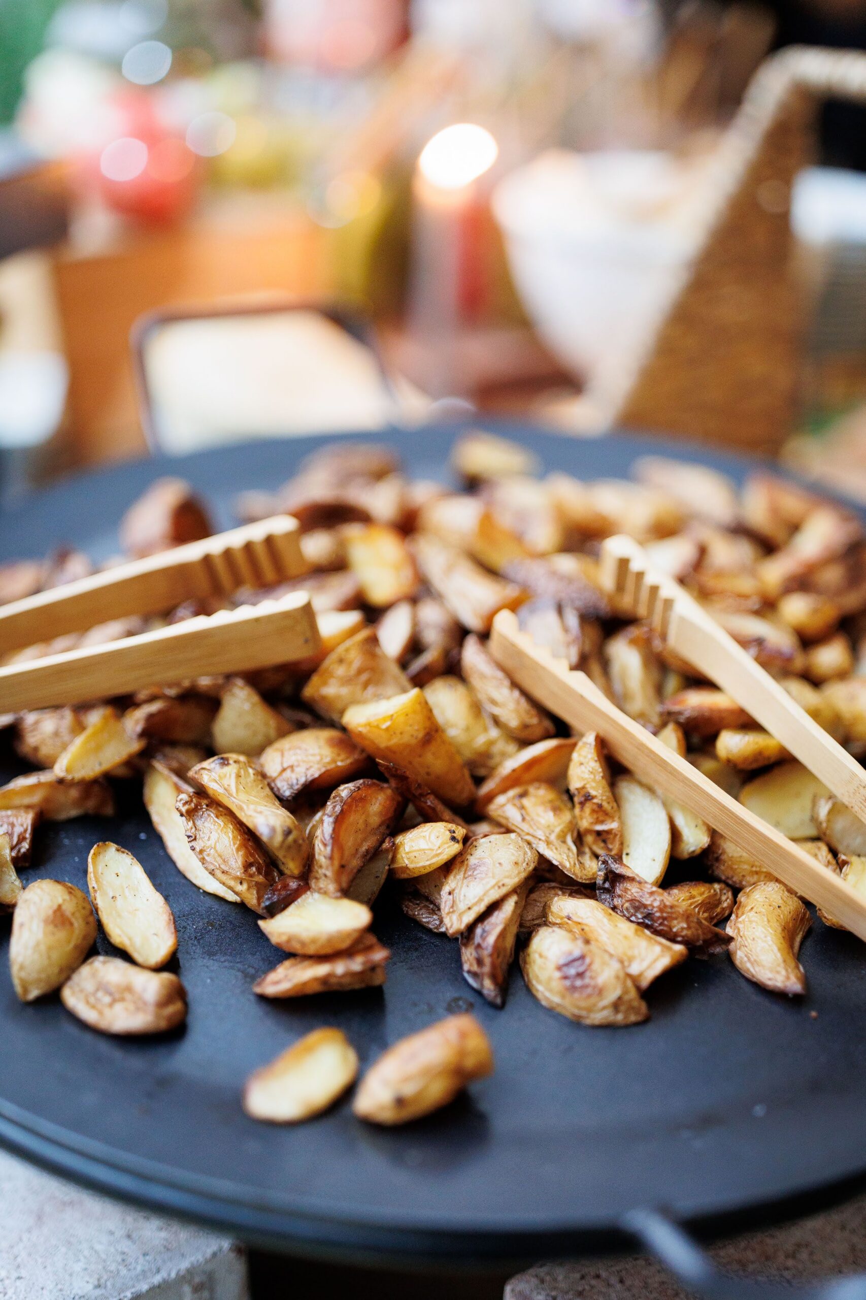 Oven roasted potatoes displayed on a buffet with serving tongs, ready for guests.