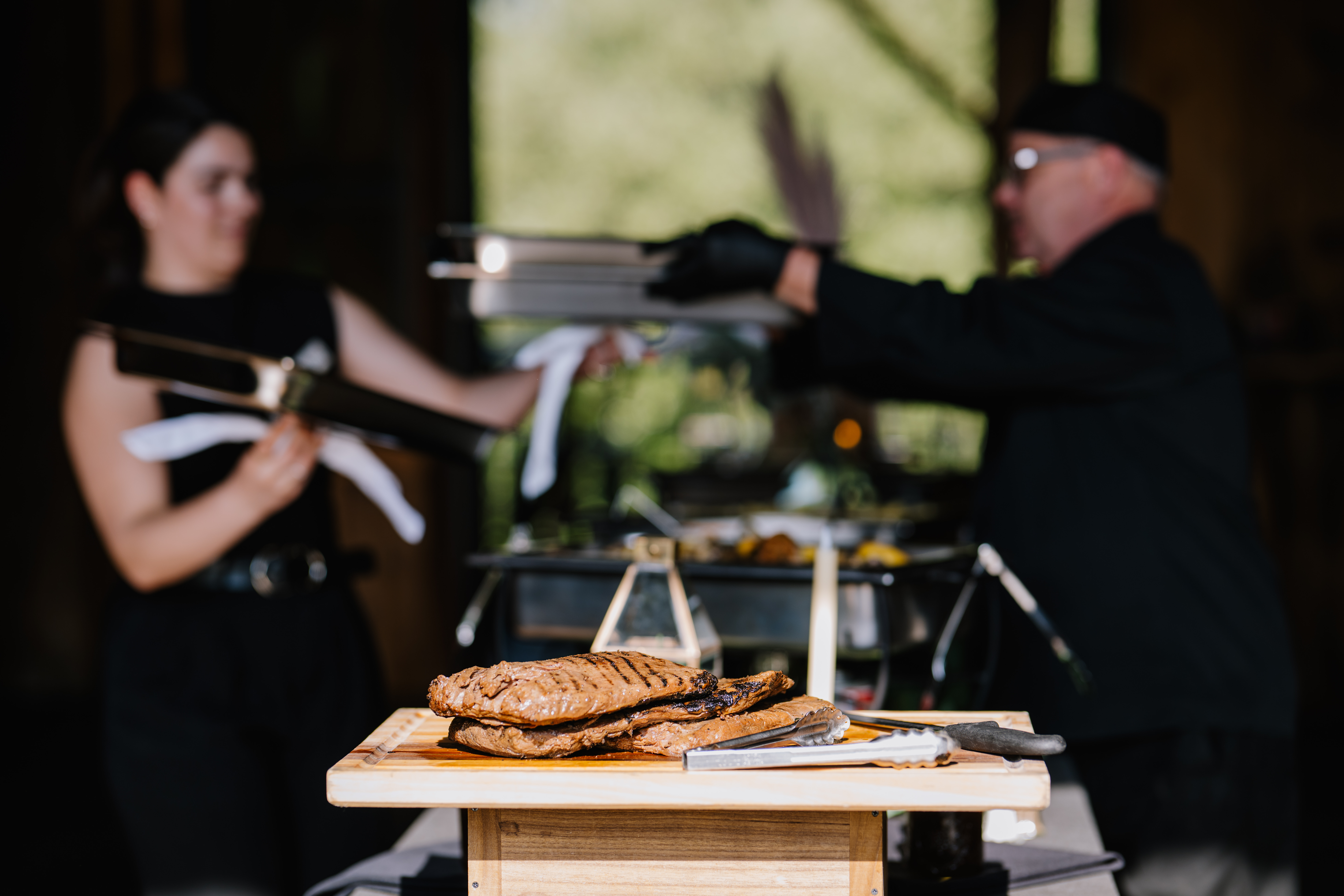 Catering team setting up a buffet station with grilled food.