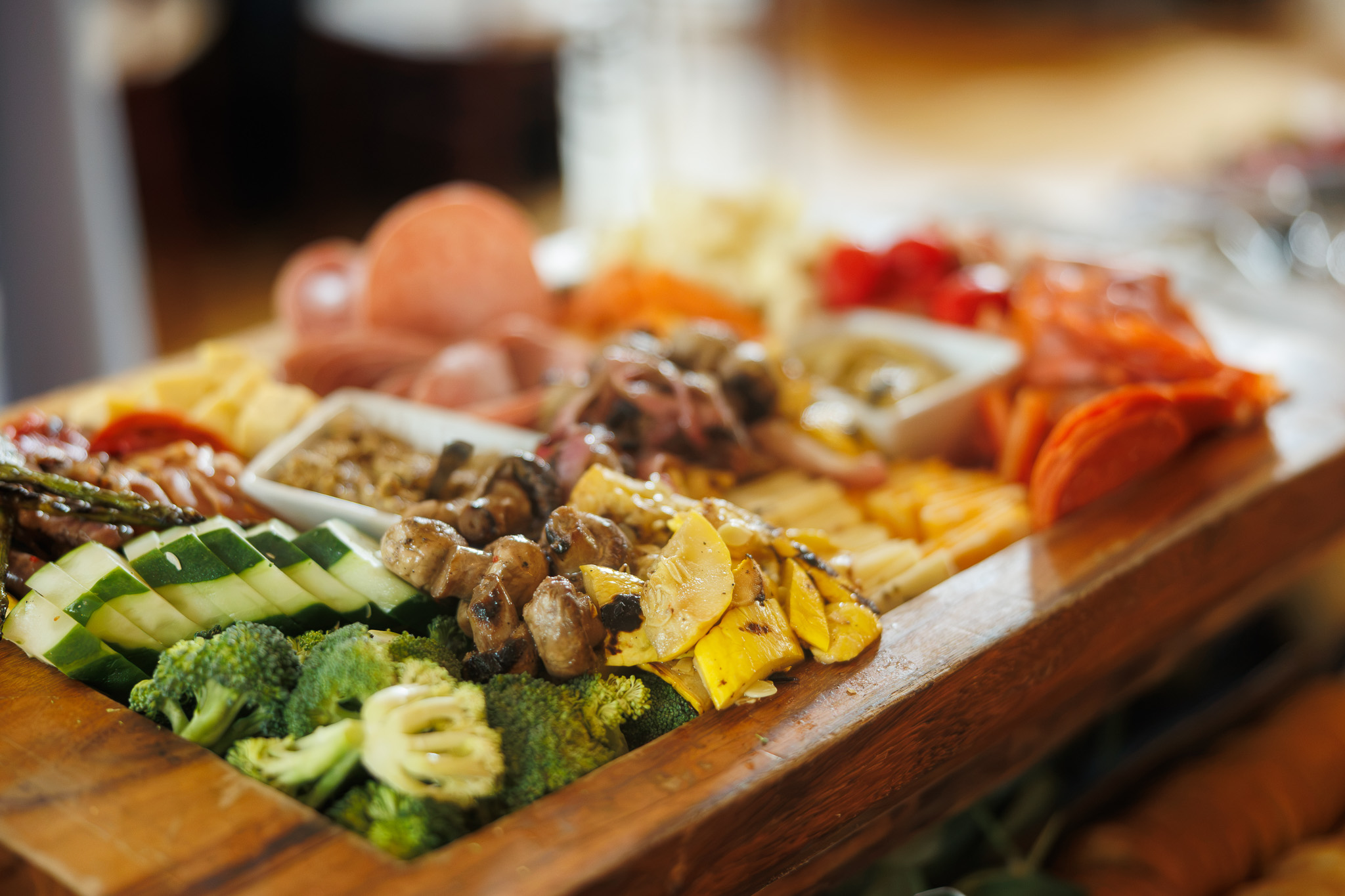 Partyman Catering Grazing Table at Corporate Event in Rochester NY Close-up of an abundant grazing table by Partyman Catering featuring artisan cheeses, cured meats, roasted vegetables, fresh vegetables, olives, and antipasti during a corporate event at The Historic German House in Rochester, NY.