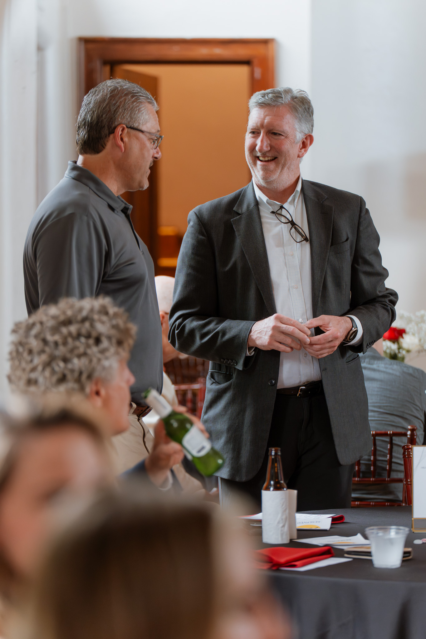 Professionals Networking at Corporate Event at The Historic German House Rochester NY Two business professionals chat during a corporate networking event at The Historic German House, surrounded by elegantly set tables and fellow attendees in Rochester, NY.