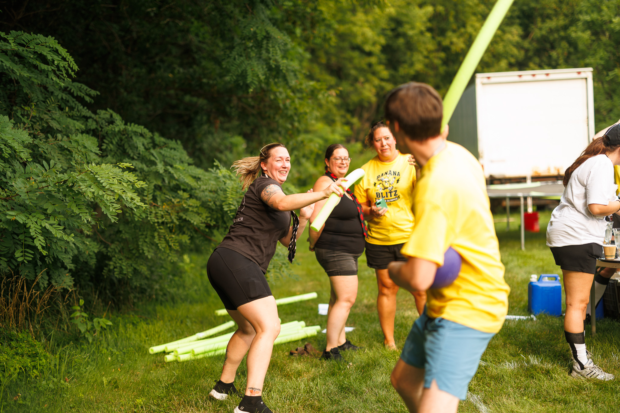 Fun Team Rivalry at Partyman Funner Olympics 2026 Partyman team members embrace the friendly rivalry of the 2026 Funner Olympics while playing outdoors with pool noodles before a challenge.