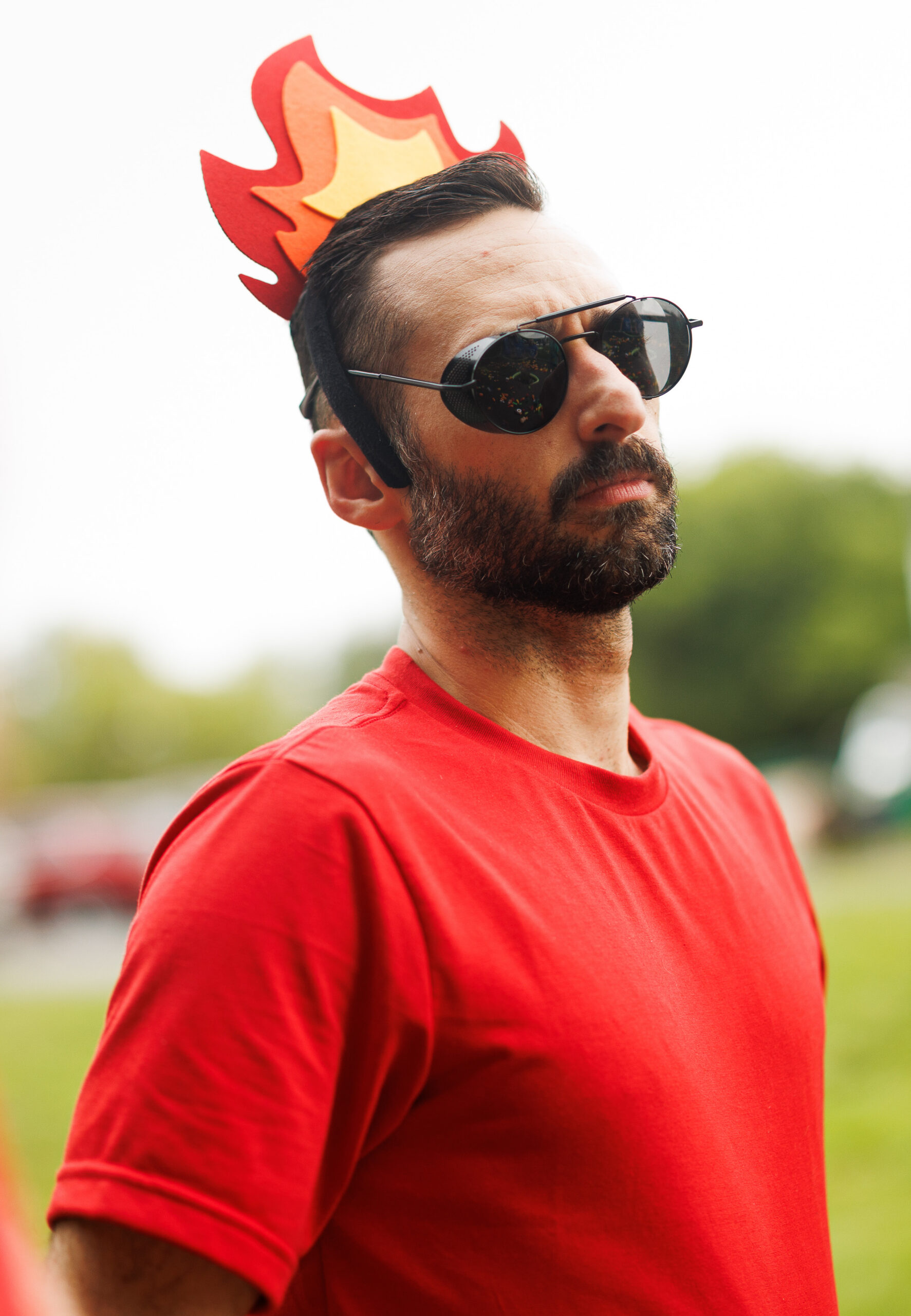 Red Team Spirit at the Partyman Funner Olympics Partyman team member in a red shirt, sunglasses, and playful flame headpiece during the outdoor Funner Olympics.