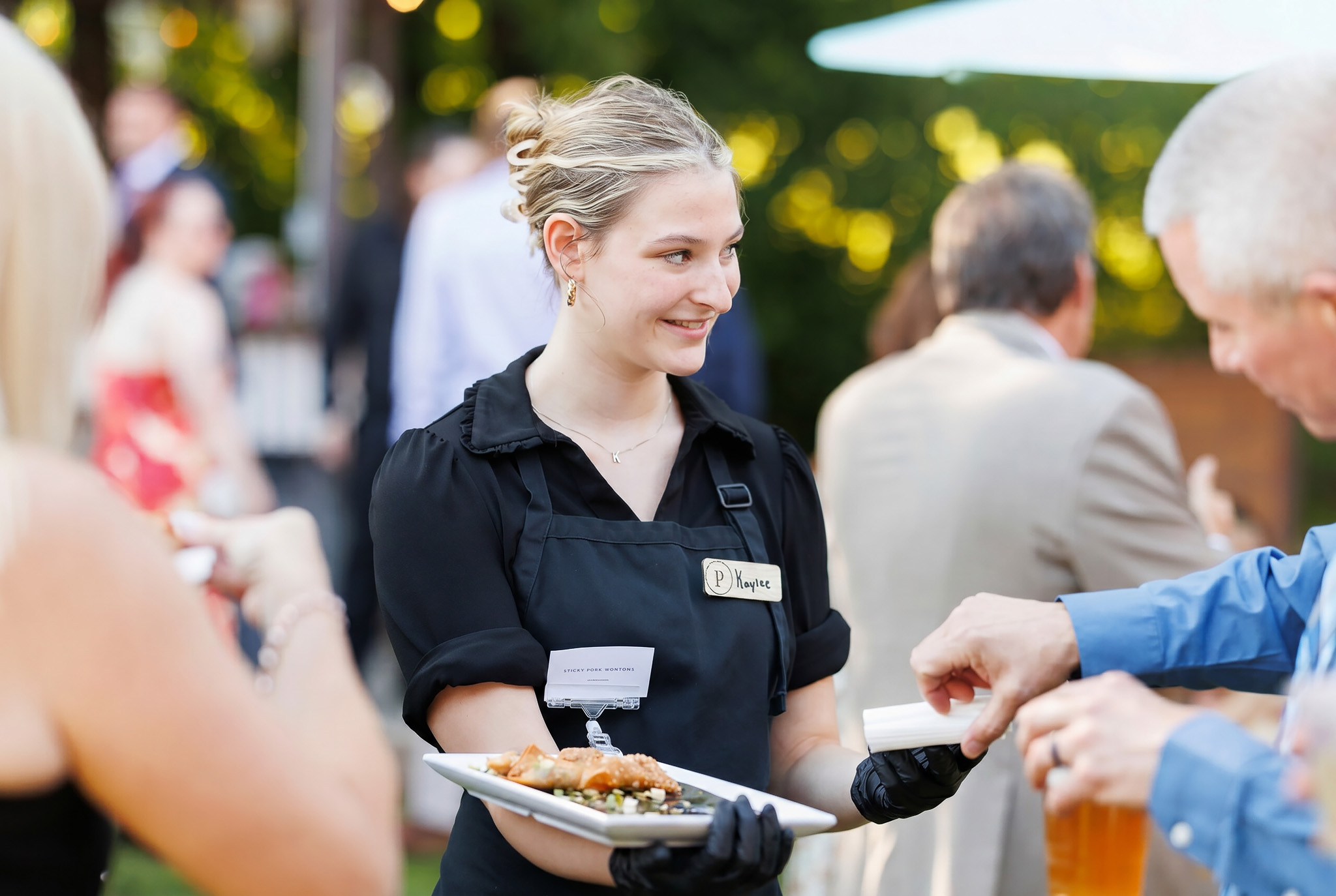 Partyman Catering Cocktail Hour Service Partyman Catering team member serving passed appetizers to wedding guests during an outdoor cocktail hour.