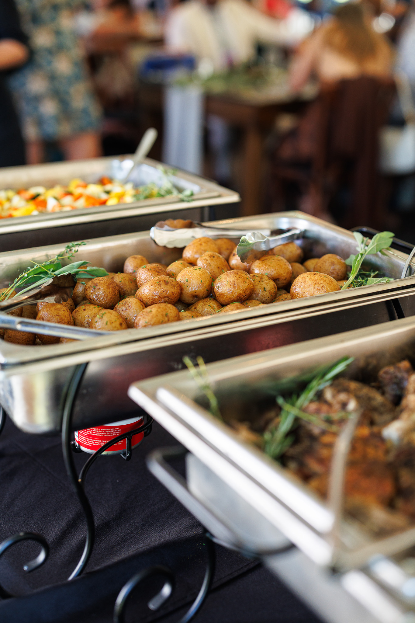 Roasted Potatoes | Wedding Buffet Catering Wedding buffet featuring seasoned roasted potatoes, herb-roasted chicken and vegetables served in chafing dishes by Partyman Catering.