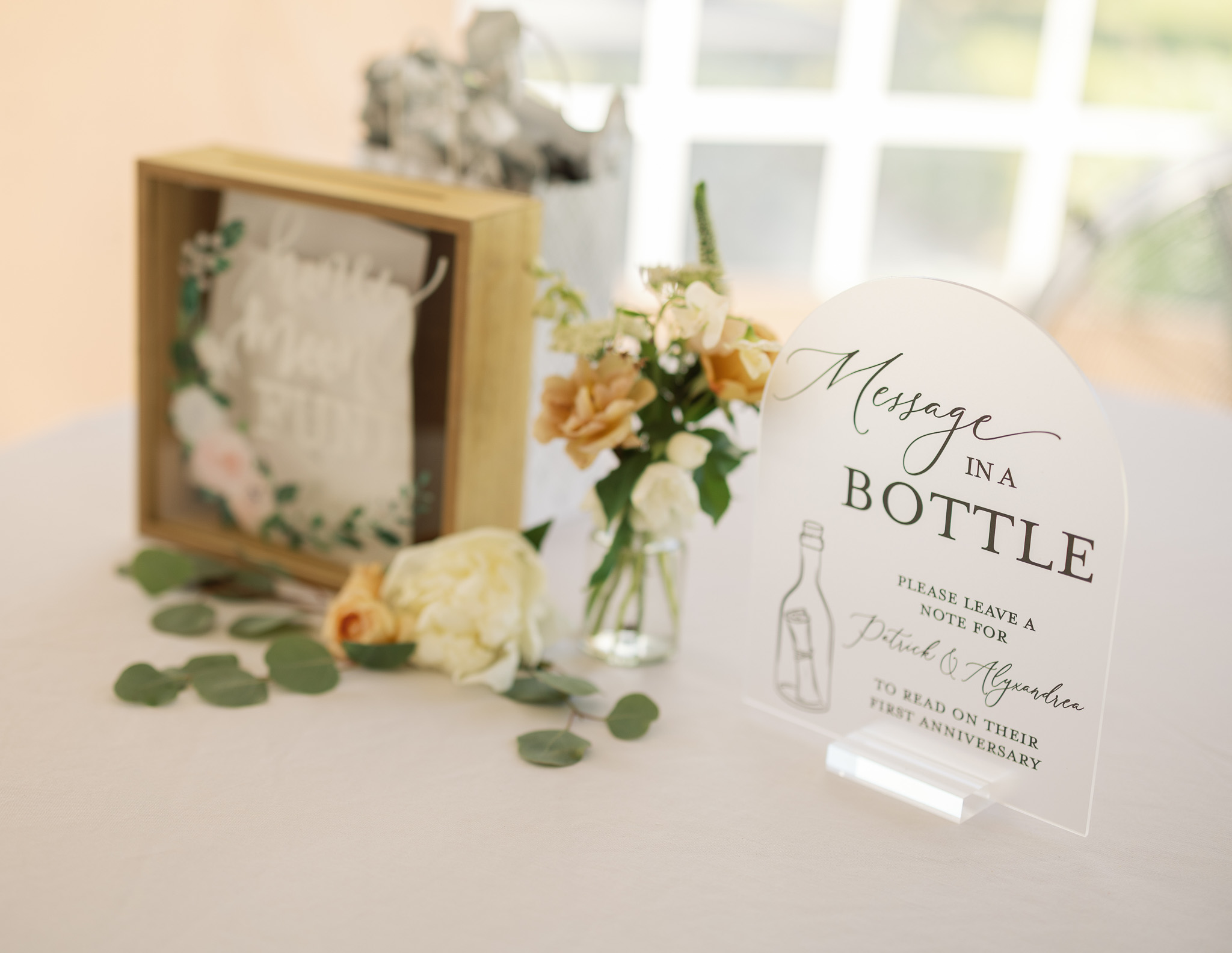 Wedding Message in a Bottle Guest Book Modern wedding guest book display inviting guests to leave anniversary messages in a bottle, styled with neutral flowers and eucalyptus greenery.