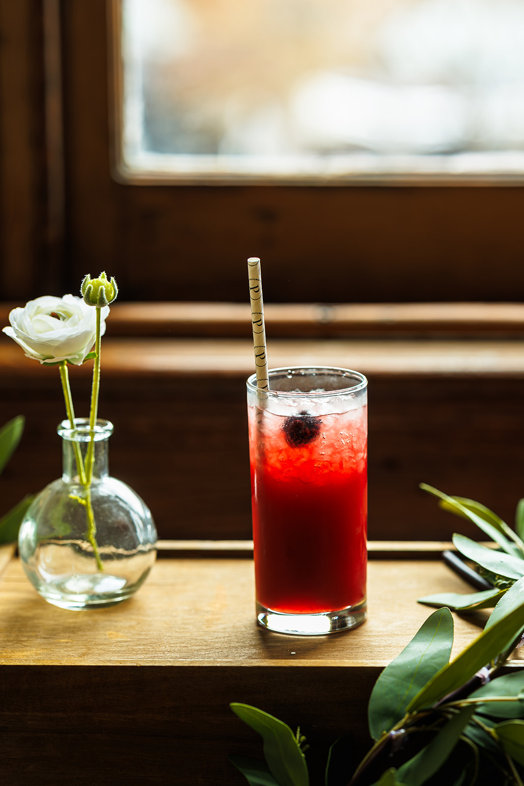 Blackberry Signature Cocktail by Partyman Catering Signature cocktail with a fresh berry garnish styled alongside a white flower and greenery by Partyman Catering.