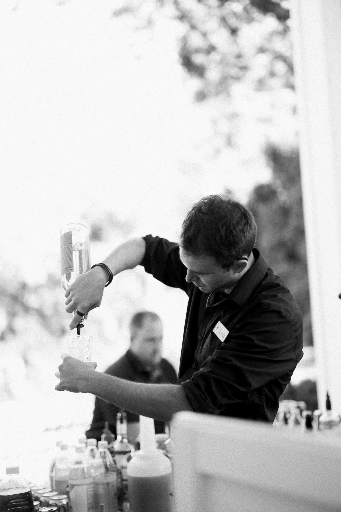 Wedding Bartender Mixing Cocktails at Whitehall Mansion Black-and-white photo of a bartender preparing a cocktail during an outdoor wedding reception at Whitehall Mansion.